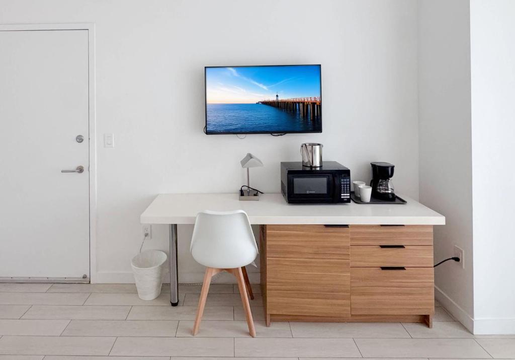 a kitchen with a desk with a microwave and a table with a chair at 30th Fl Beachwalk Studio Bay Balcony in Hallandale Beach
