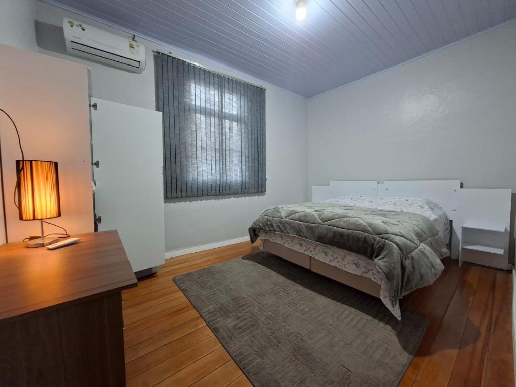 a bedroom with a bed and a desk with a lamp at Casa Finger próx do Centro e do Núcleo de Casas Enxaimel ambiente familiar in Ivoti