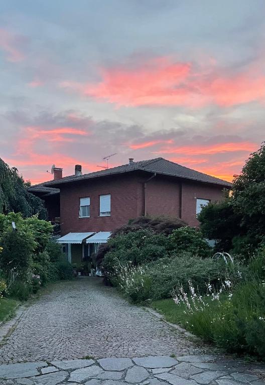 a brick house with a sunset in the background at B&B Villa Giardini Susanna in Veruno