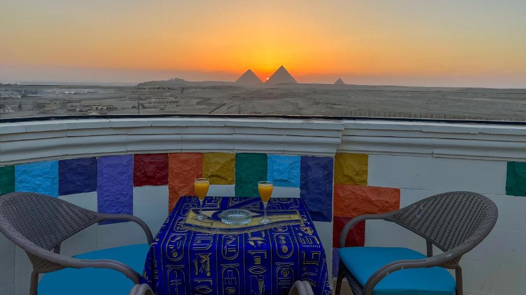 a table with drinks on a balcony with the pyramids at Atlantis Pyramids Inn in Giza