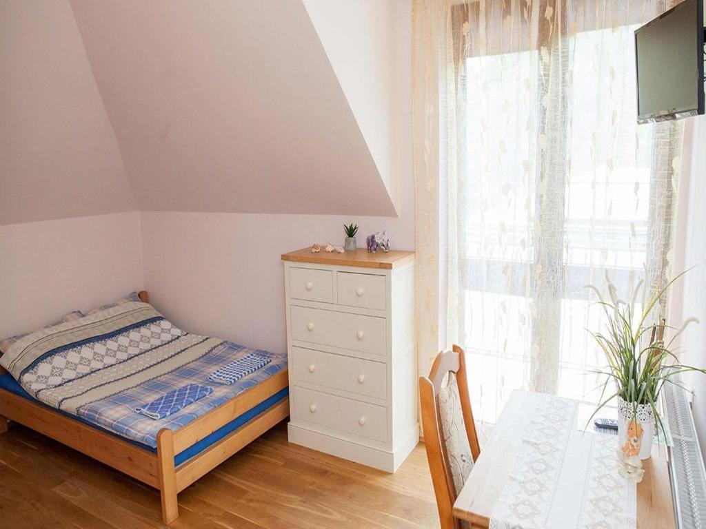 a bedroom with a bed and a dresser and a window at 4-person room, sauna, Masuria in Ruciane-Nida