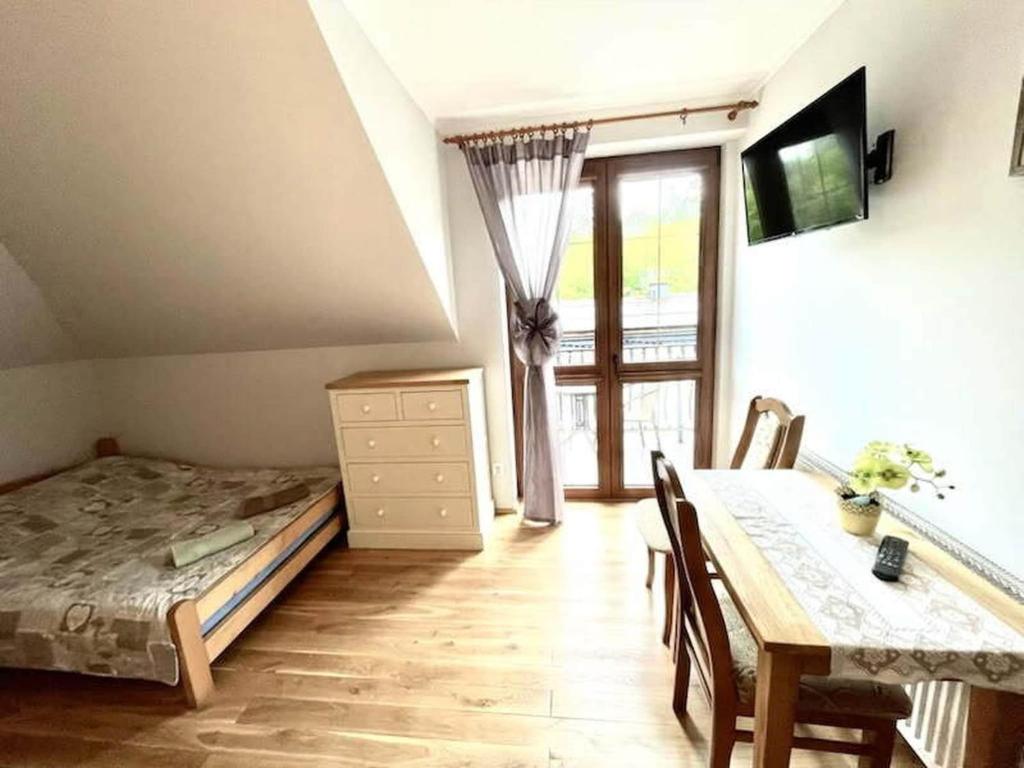 a bedroom with a bed and a table and a window at Triple room, sauna, Masuria in Ruciane-Nida