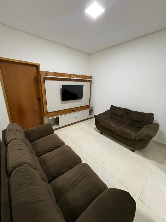 a living room with a couch and a flat screen tv at Hospedaria Santa Inês in Cachoeira Paulista