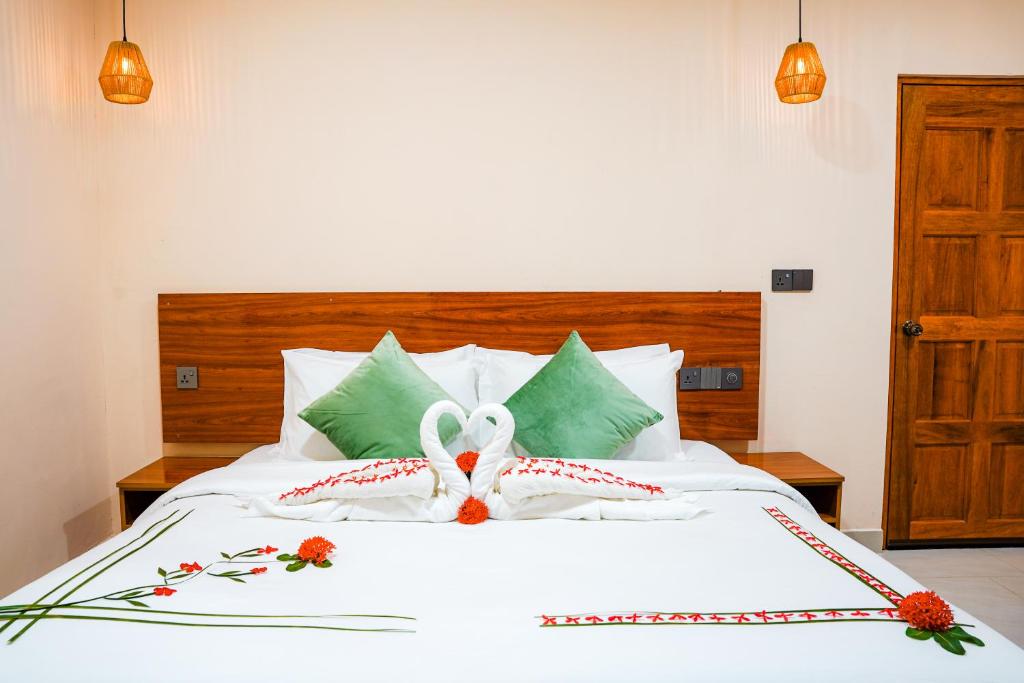 a bedroom with a white bed with flowers on it at Naeco Select Pearl in Hanimaadhoo