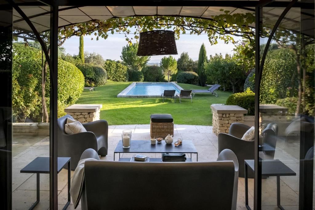 a patio with a table and chairs and a pool at Mas De Rosemarie in Joucas