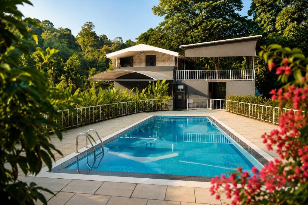 a swimming pool in front of a house at T Hill Vythiri Pool Resort in Vythiri