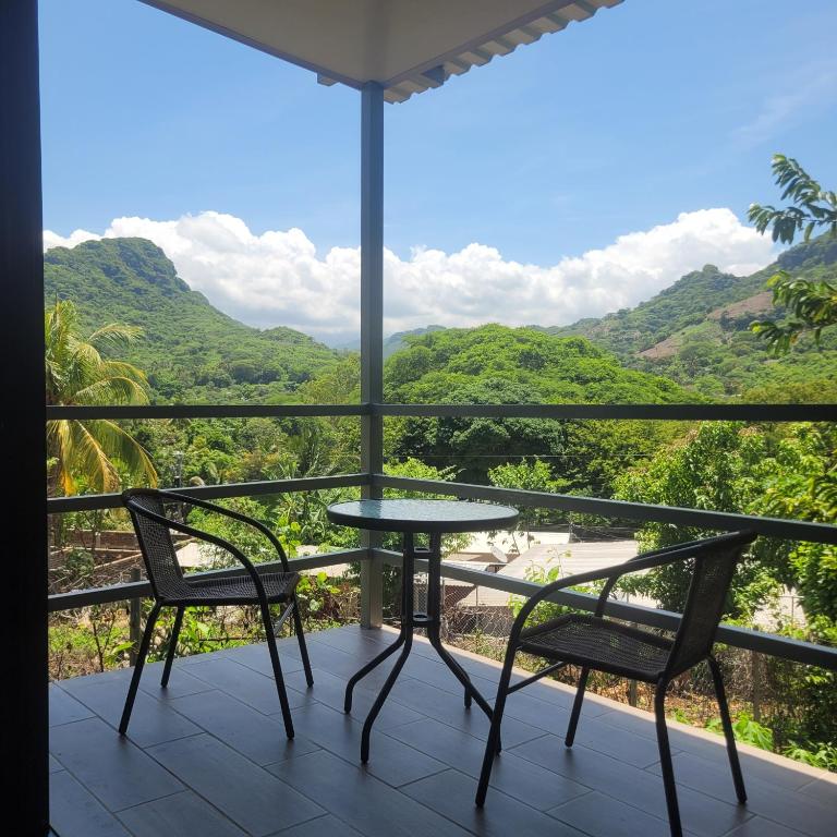 a table and chairs on a balcony with mountains in the background at Torogoz Apartment km61 5 in Jicalapa