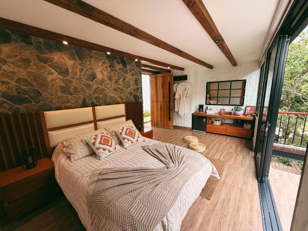 a bedroom with a bed and a stone wall at Glamping La Cima in San Gil