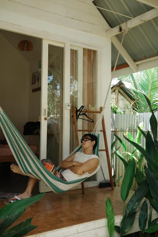 a man sitting in a hammock on a porch at Verde Bungalows Siargao in General Luna