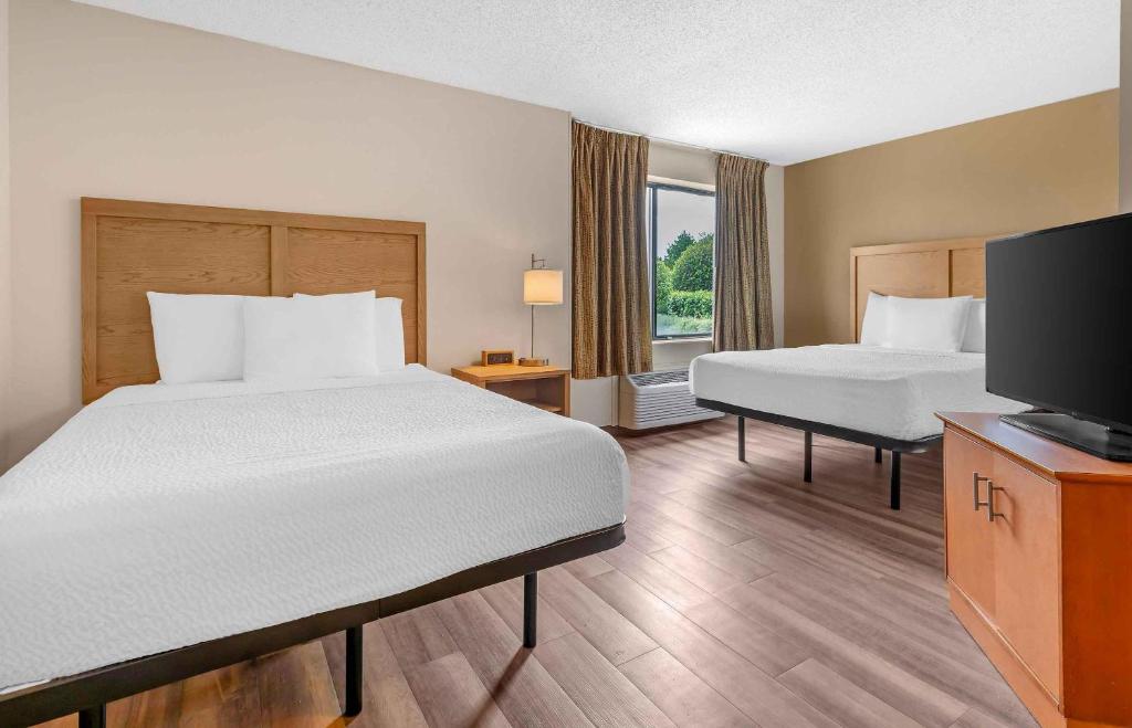 a hotel room with two beds and a flat screen tv at Extended Stay America Suites - Fort Worth - Fossil Creek in Fort Worth