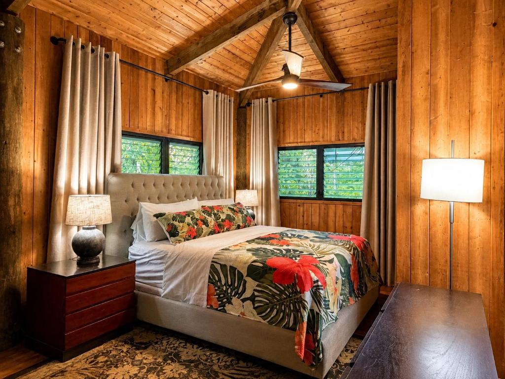a bedroom with a bed in a room with wooden walls at Tiki Treehouse in Keaau