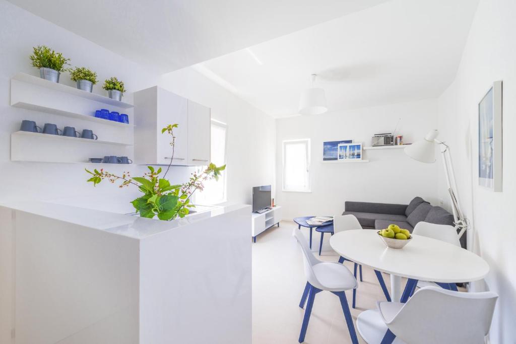 een witte woonkamer met een witte tafel en stoelen bij Puolo Seaside Apartment in Massa Lubrense