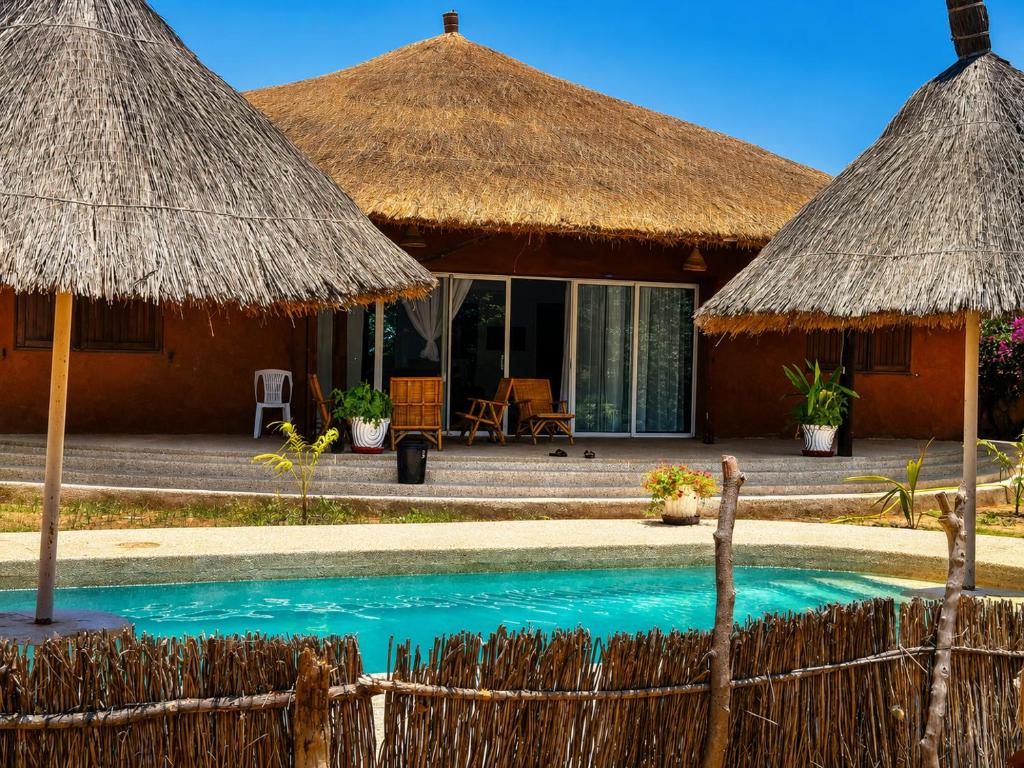 a resort with a pool and thatched umbrellas at Villa Farou in Mbour