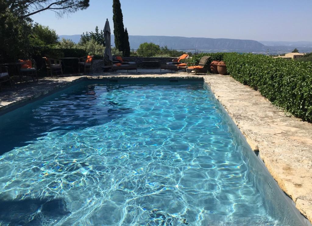 a swimming pool with blue water in a yard at La Borie en Provence in Gordes