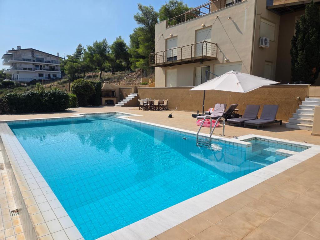 a swimming pool with an umbrella next to a building at Azure Theologos Villa in Theologos