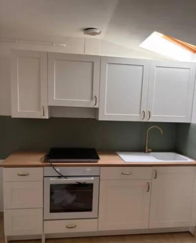 a kitchen with white cabinets and a sink at Kirollos in Montlhéry