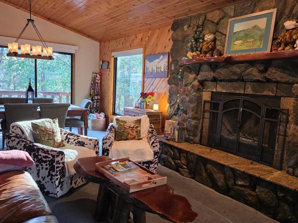 a living room with a stone fireplace in a house at Four Seasons Getaway-Private Hot Spa with Pine Tree Views-Walk to Village and Pineknot Trailhead-Plus King Bed! in Big Bear Lake