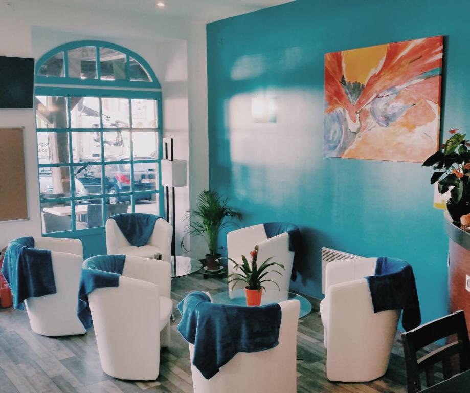 a waiting room with white chairs and a blue wall at Hôtel Les Comtes de Pardiac in Marciac