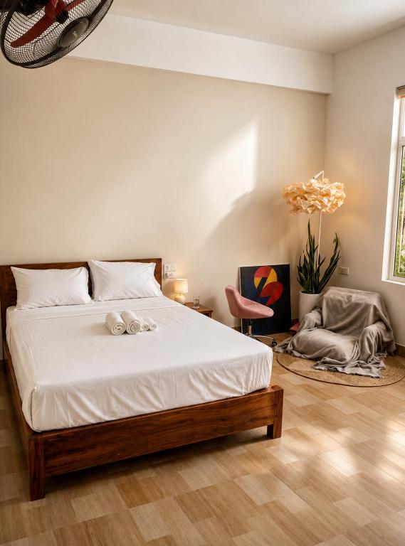 a bedroom with a large bed and a chair at Tam Coc Sylvani Homestay in Vũ Lâm
