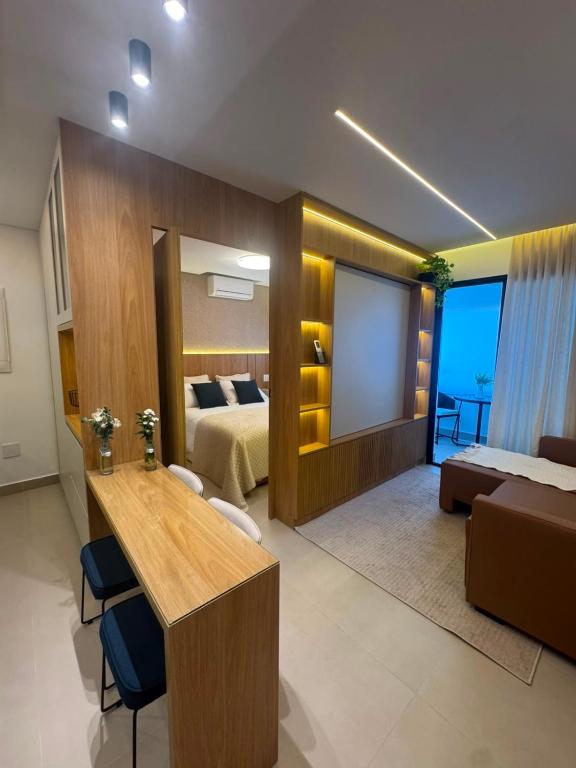 a living room with a bed and a desk in a room at Studio Mandarim Campolim in Sorocaba