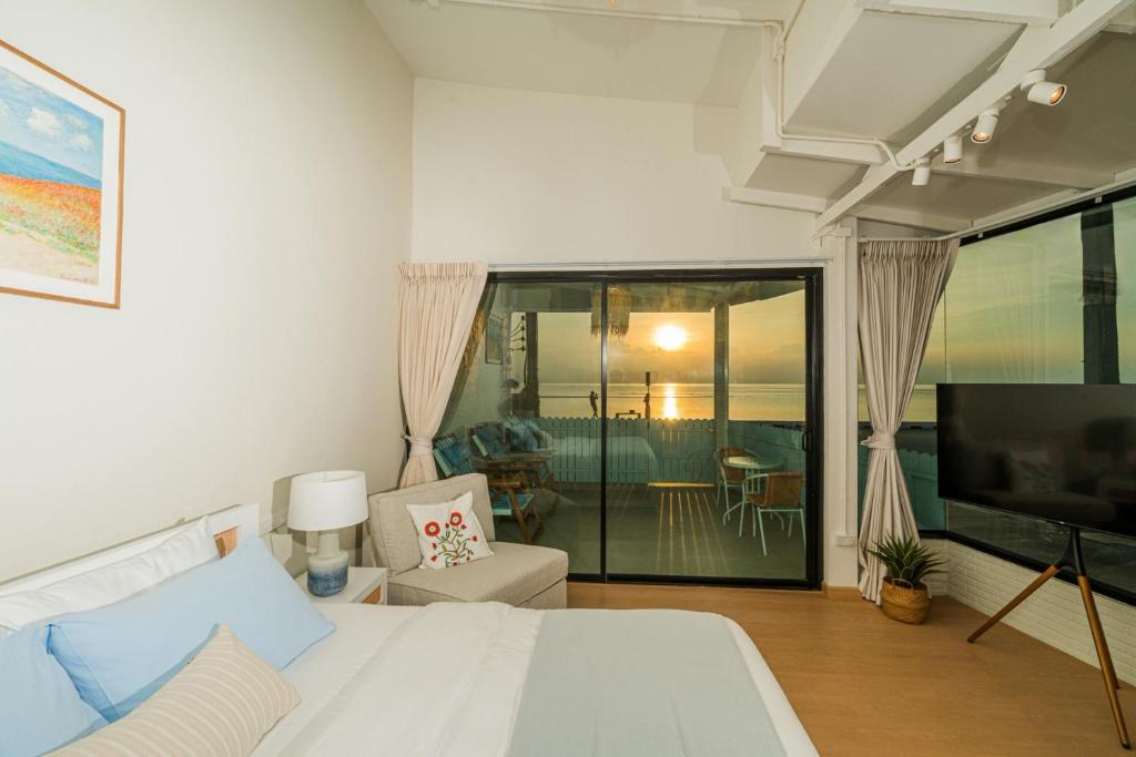 a bedroom with a bed and a tv and a living room at Sea Salt Stay Samui in Nathon