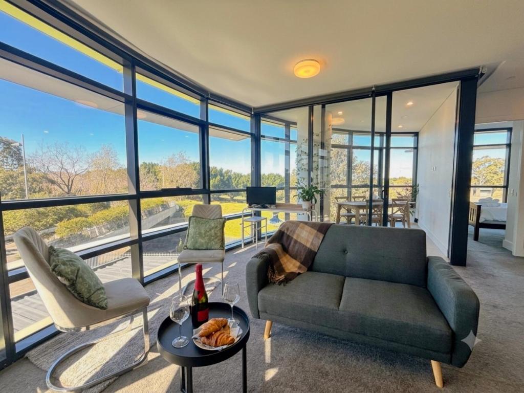 a living room with a couch and a table at Floor-to-Ceiling Park View Oasis at Olympic Park Free Parking Sleeps 5 in Sydney