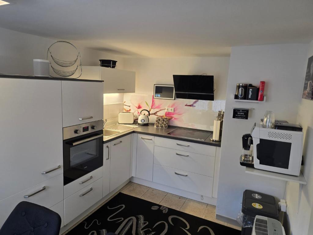 a small kitchen with white cabinets and appliances at Ferienhaus Bergrath in Zell an der Mosel