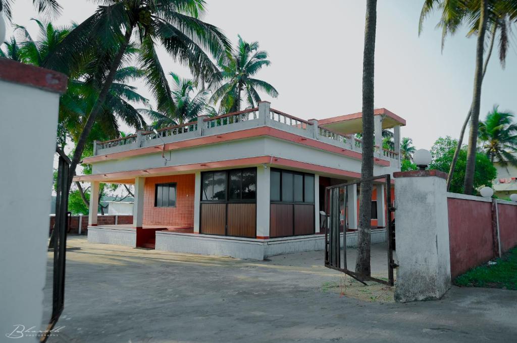 a building with palm trees in front of it at Sattva camps and cottages - Udupi in Udupi