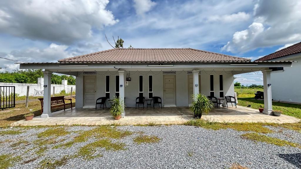 a small white house with chairs and a patio at Cahaya roomstay in Kangar