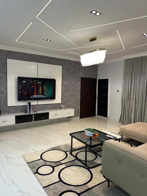 a living room with a tv and a couch and a table at Grey Ivy Apartment in Abuja