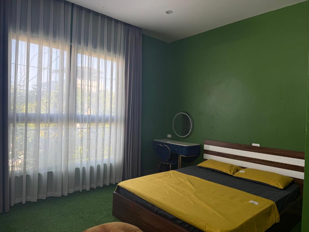 a green bedroom with a bed and a window at She Stay in Hòa Bình