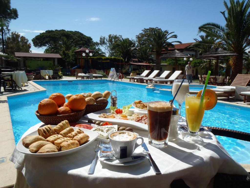 a table with food and drinks next to a pool at Vergos Hotel in Vourvourou