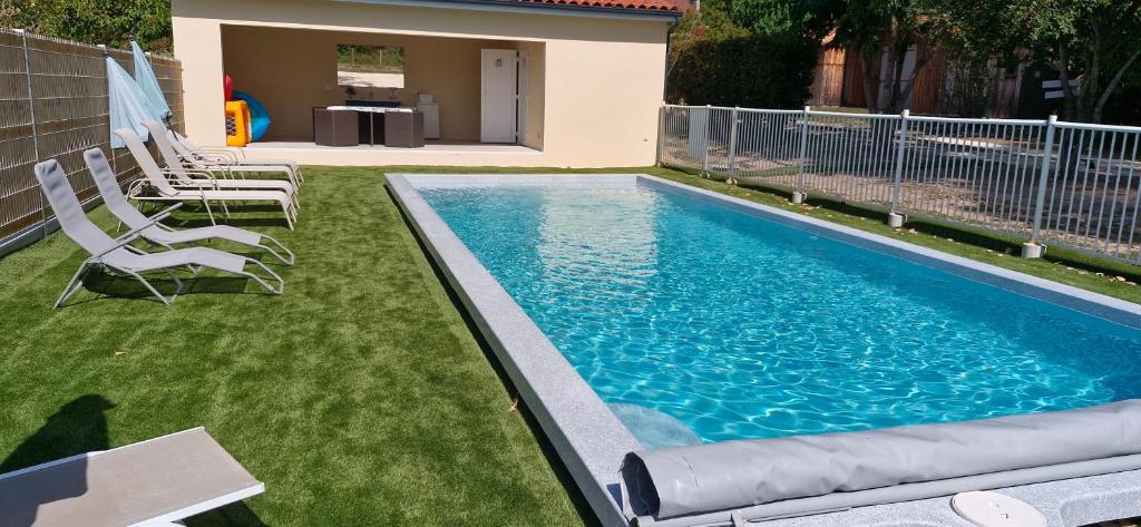 a swimming pool with chairs in a yard at Gîtes le clos du verger avec piscine chauffée commune in Maurens
