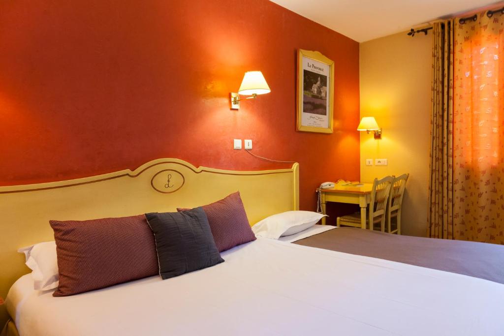 a hotel room with two beds and a table with a desk at LOGIS HOTEL & RESTAURANT L'ETAPE Bouc Bel Air - Gardanne in Bouc-Bel-Air