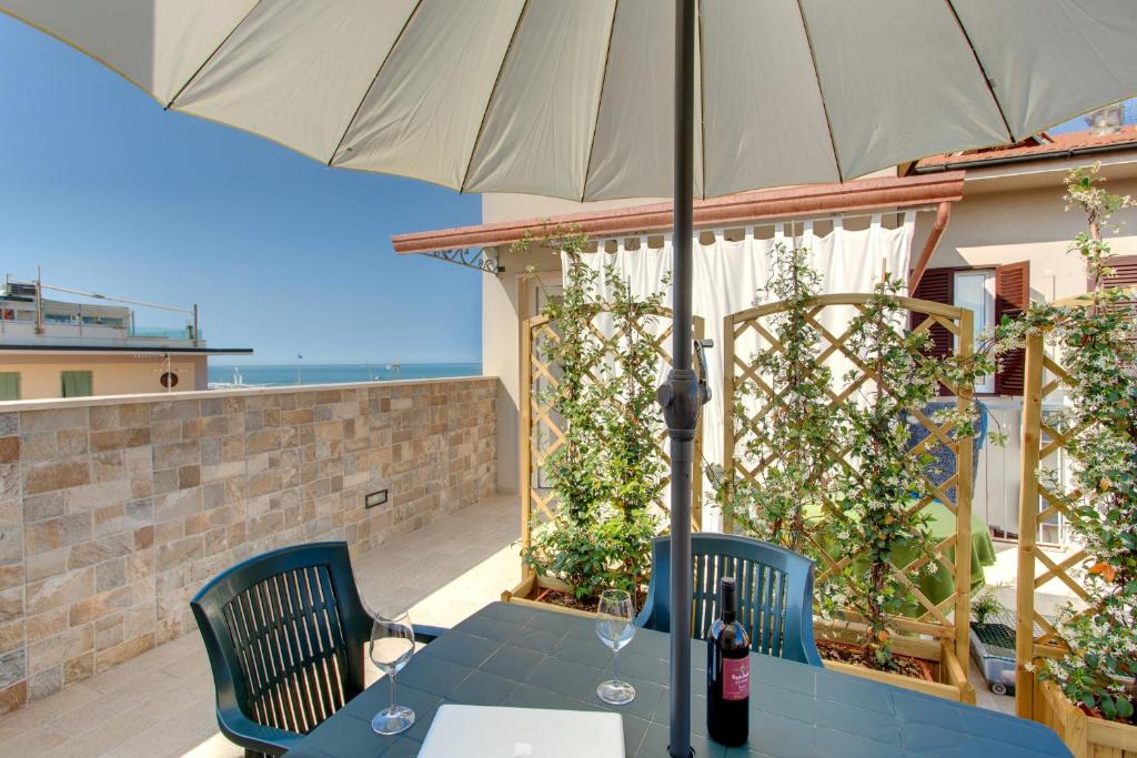 リド・ディ・カマイオーレにあるResidence Sea view Biagiのパティオ(パラソル付きのテーブルと椅子付)