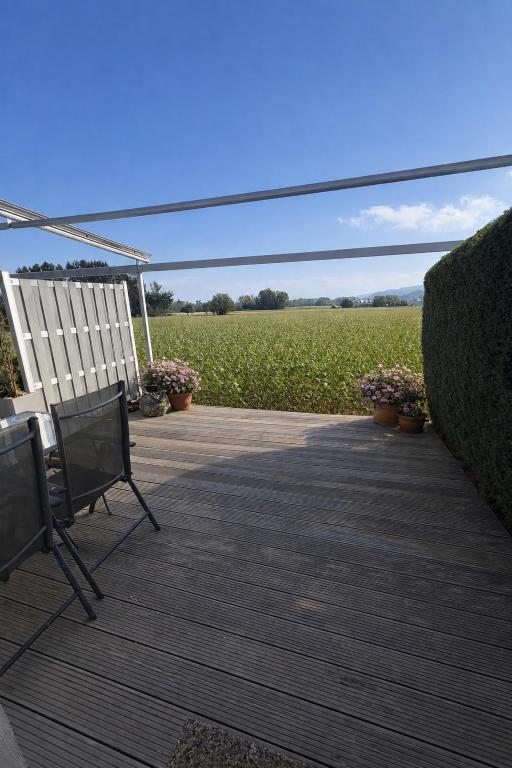 a patio with two chairs and a field of flowers at Loipersdorf Living - Golf & Therme in Loipersdorf bei Fürstenfeld