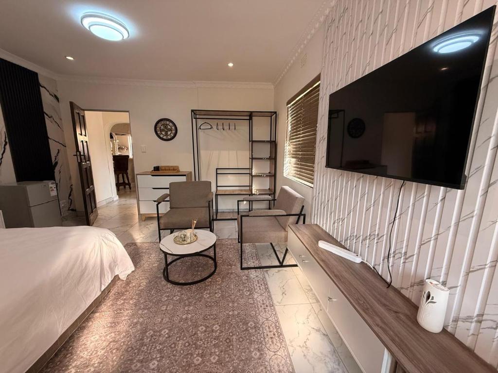 a bedroom with a bed and a couch and a table at The Benjamin Guest House in Edenvale