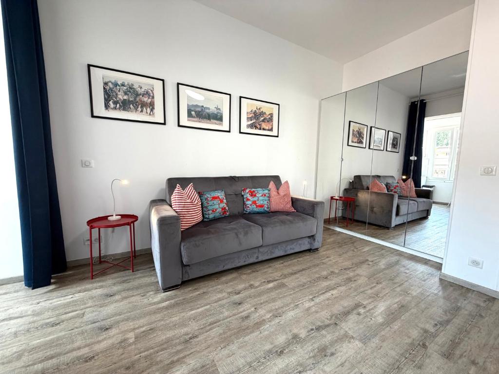 a living room with a gray couch and a mirror at Palace Riviera Studio - Plages & Centre Menton in Menton