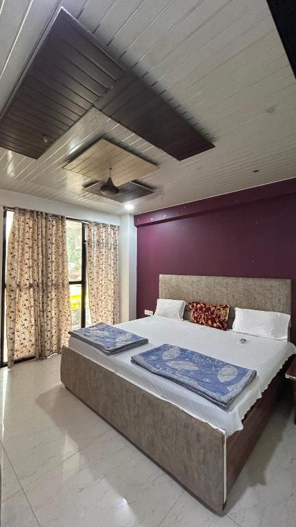 a bedroom with a large bed with a purple wall at The MEERA in Godarpura