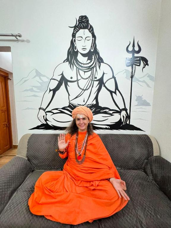 a woman in an orange dress sitting on a couch at Shiv Kothi Home Stay in Varanasi