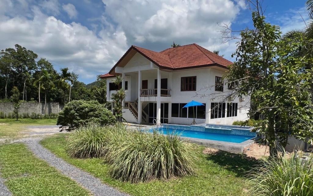 a house with a swimming pool in front of it at theorenda 002 in Koh Samui