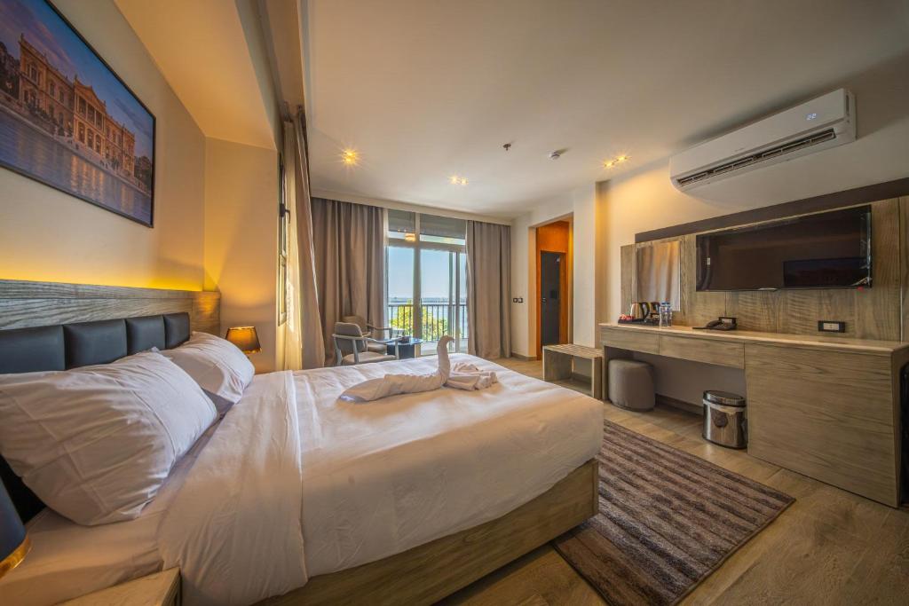 a hotel room with a large bed and a television at Regency Nile Hotel Assuit in Al Ḩamrāʼ