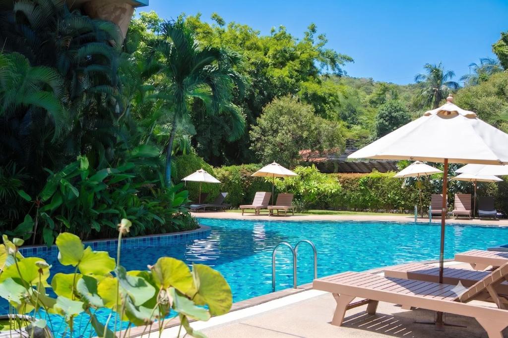 a pool at a resort with chairs and umbrellas at Seaflower Bungalows in Srithanu