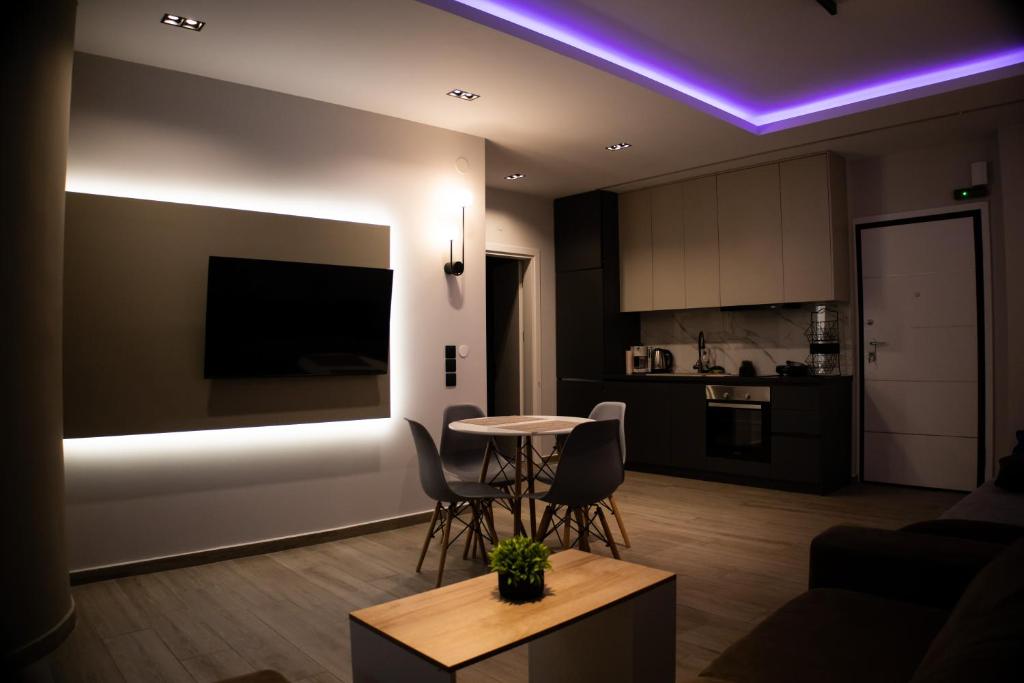 a living room with a table and a kitchen with purple lights at Kalma Apartment Xanthi Center in Xanthi