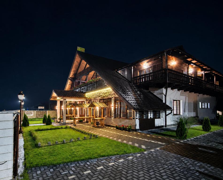 a large wooden building with lights on it at night at Vidra Dacica in Vidra