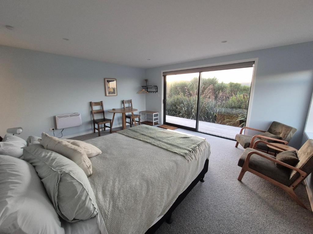 a bedroom with a large bed and a large window at Unit at Curio in Curio Bay