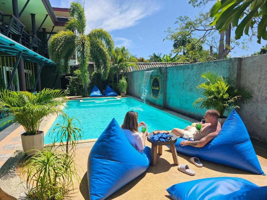 a family sitting on pillows next to a swimming pool at Cha-Tinnie Hotel in Phra Ae beach