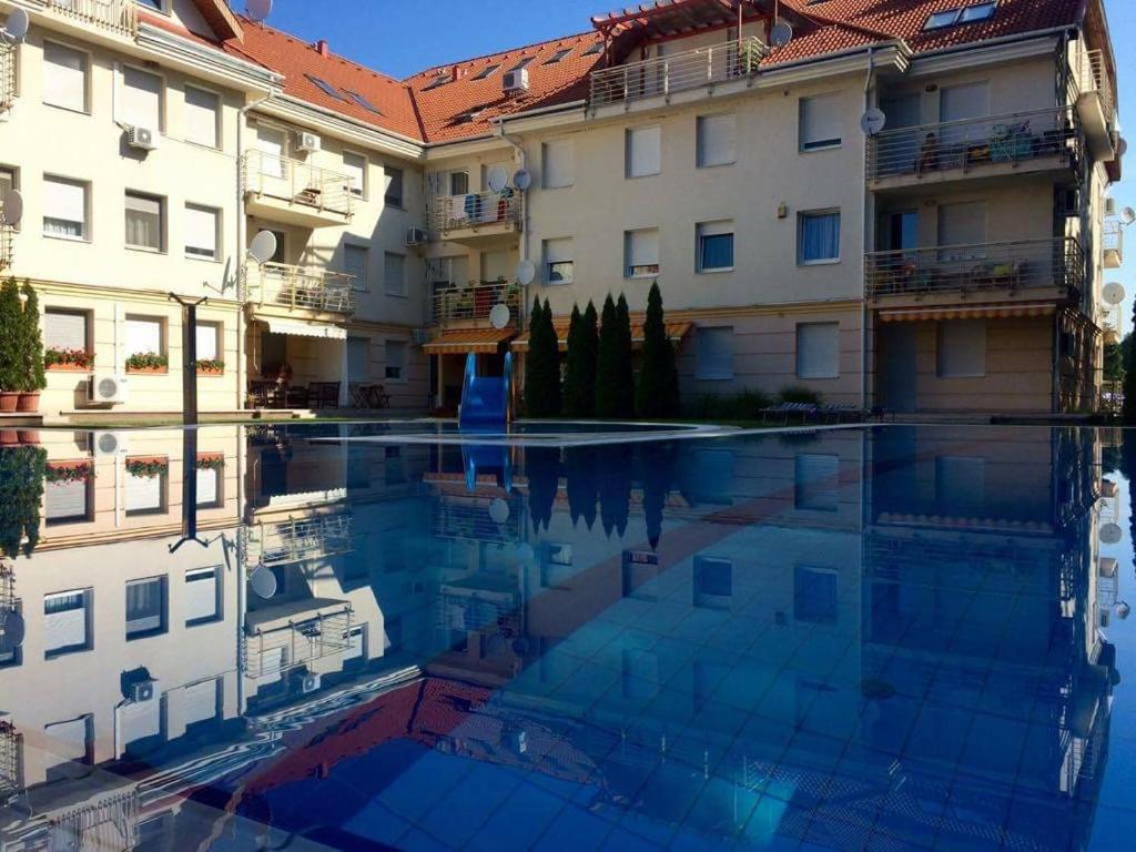 a swimming pool in front of a building at Relax Apartman in Hajdúszoboszló