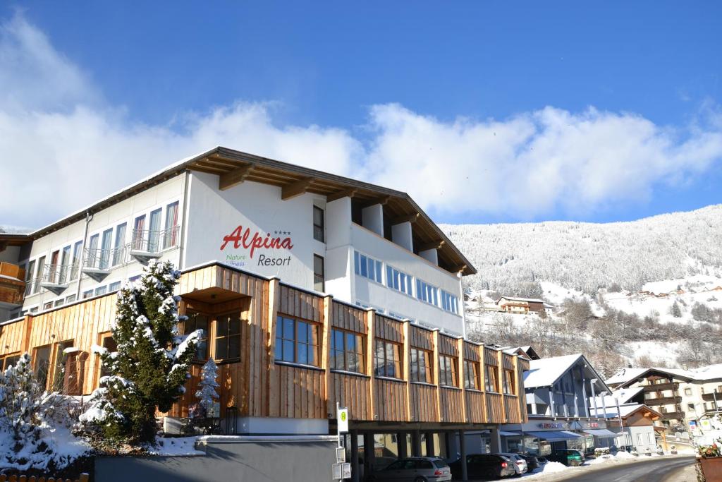 a building with a mountain in the background at Hotel Alpina nature-wellness in Wenns