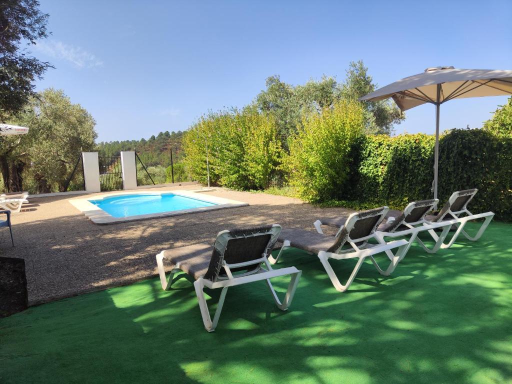 a group of chairs and an umbrella next to a pool at Casas Rurales Los Montes in La Corte